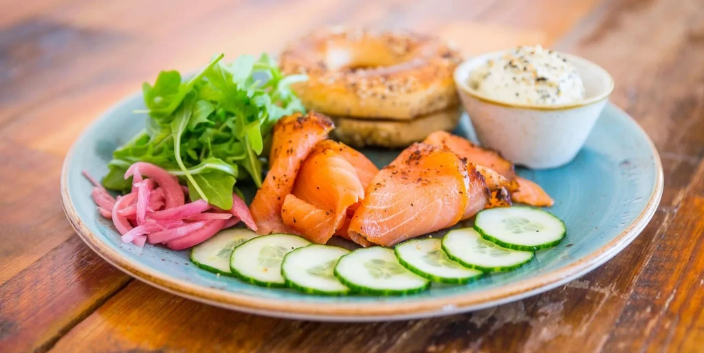 Smoked salmon, arugula, cucumber, and pickled onions with bagels and cream cheese.