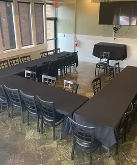 Empty event room with U-shaped table, black chairs, and city view.