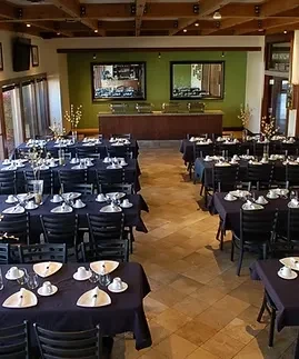 Restaurant dining area with set tables, buffet, and wooden beams.