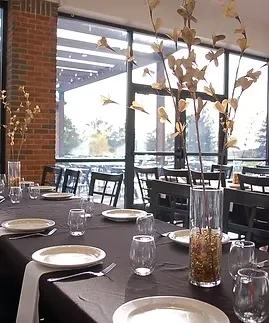 Long restaurant table set with place settings and decorative branch centerpieces.