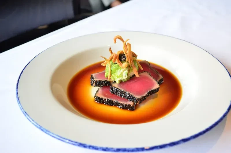 Seared tuna with black sesame, avocado, and crispy topping in a bowl.