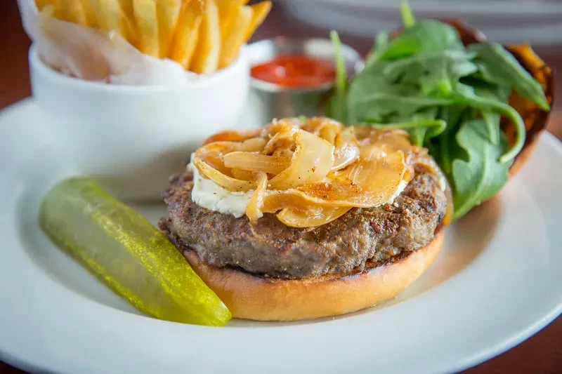 Gourmet burger, caramelized onions, cheese, pickle, fries, and arugula salad.