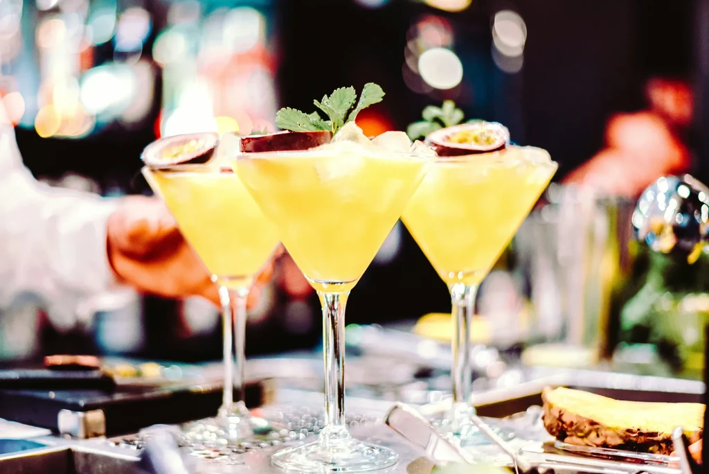 Three yellow martini cocktails with passion fruit, mint, and ice.