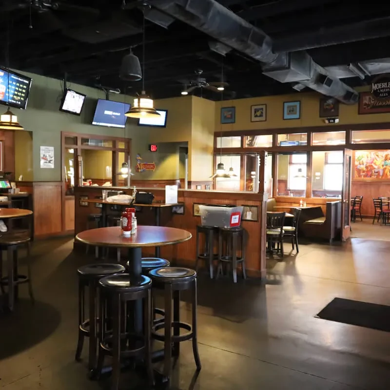 Empty casual sports bar with high-top tables, booths, and multiple TVs.