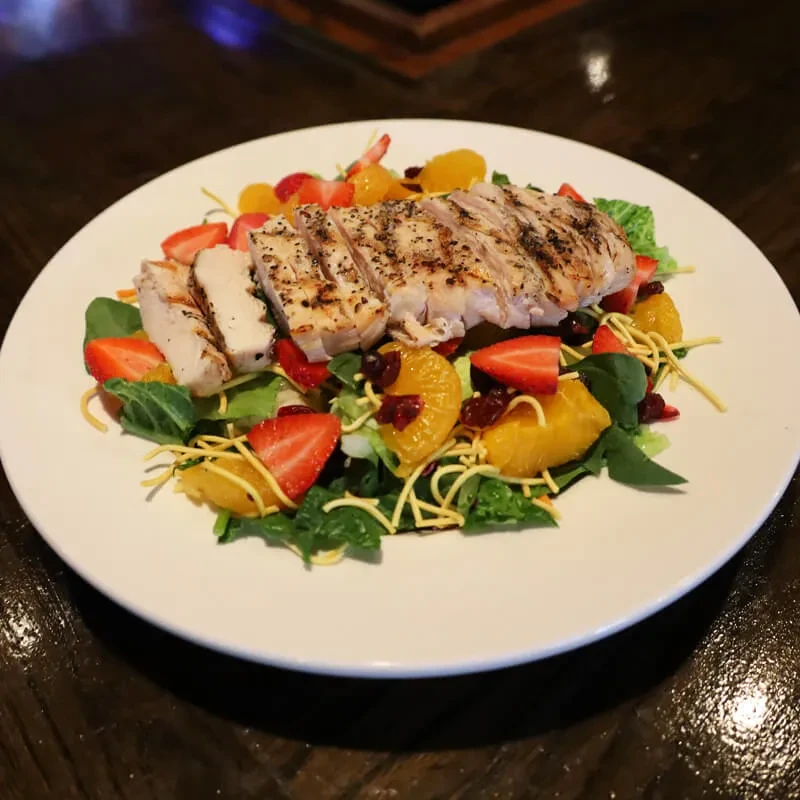 Grilled chicken salad with greens, strawberries, orange, cranberries, and wontons.