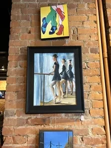 Three vertically stacked framed artworks on a rustic brick wall.