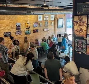 Bustling cafe interior with exposed brick, art, and many patrons.
