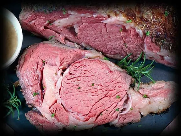 Roasted medium-rare prime rib, sliced, with rosemary and au jus.