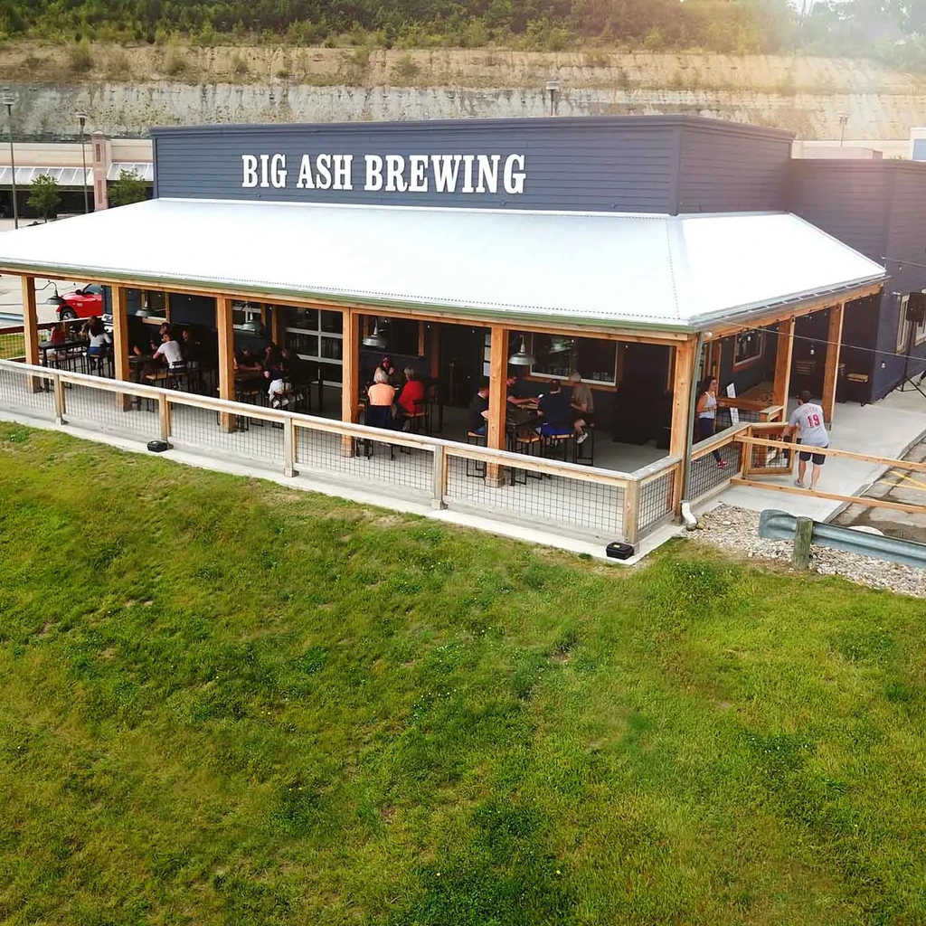 Big Ash Brewing exterior, large patio with people, grassy slope.