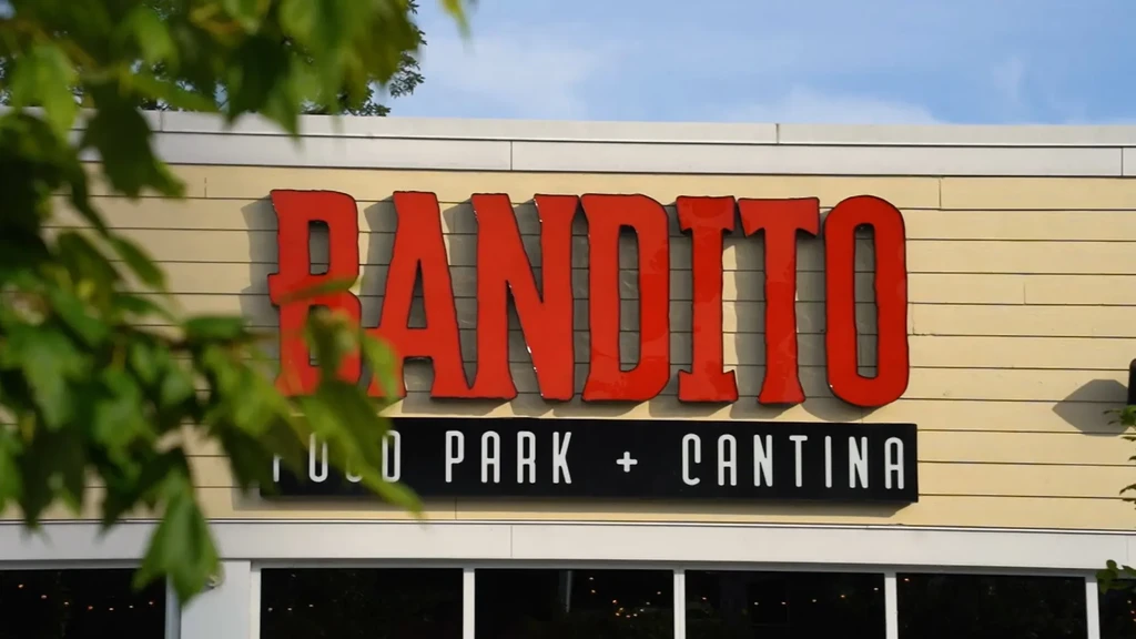 Bandito Food Park + Cantina sign on building, blurred foliage.