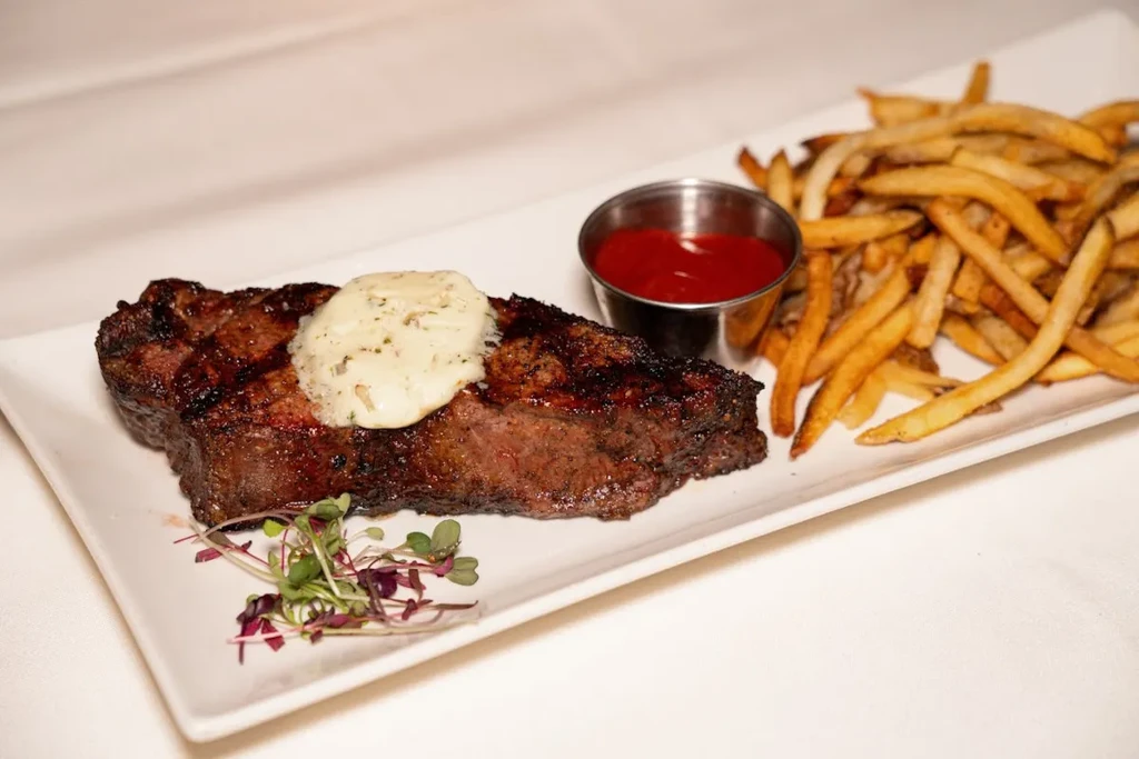 Grilled steak with melting butter, golden fries, ketchup, microgreens.