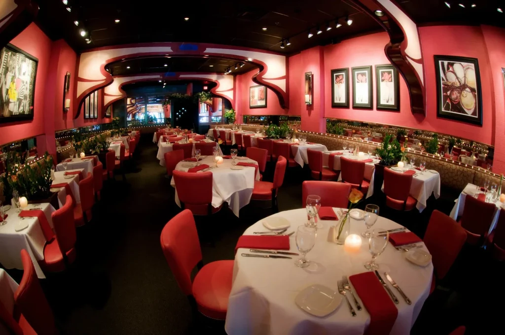 Empty pink-walled restaurant dining room with white tablecloths and candles.