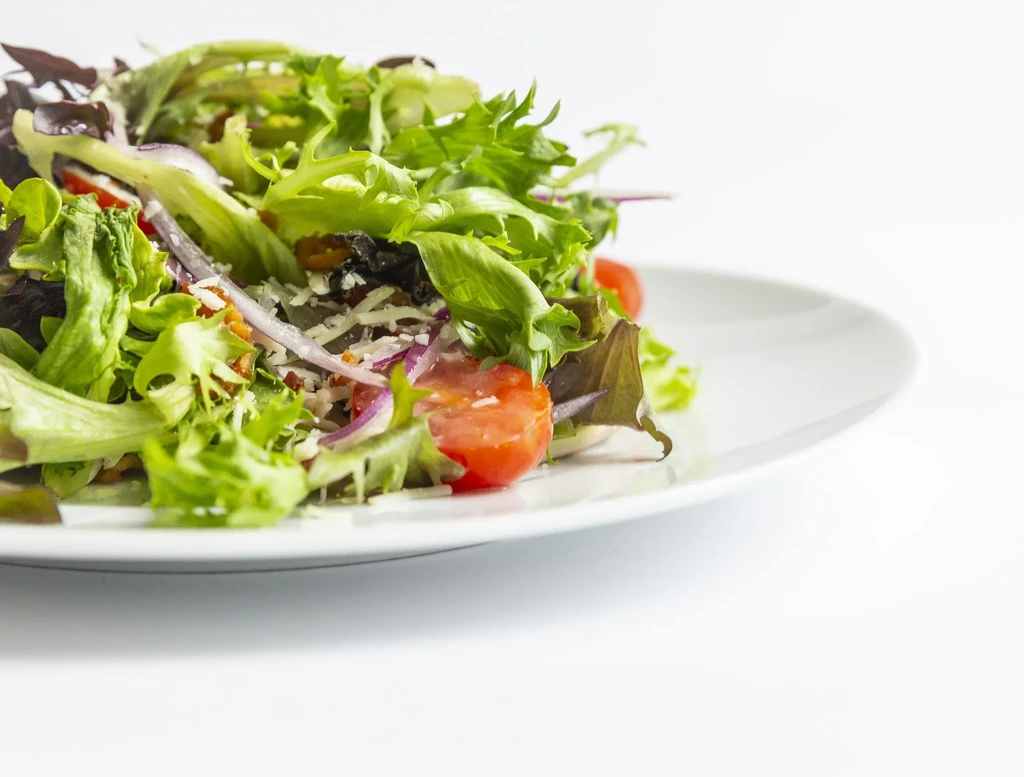 Vibrant mixed green salad with tomatoes, red onions, and cheese.