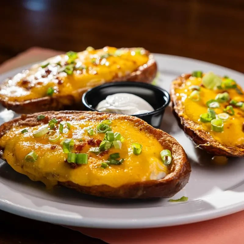 Three potato skins topped with cheese, bacon, green onions, and sour cream.
