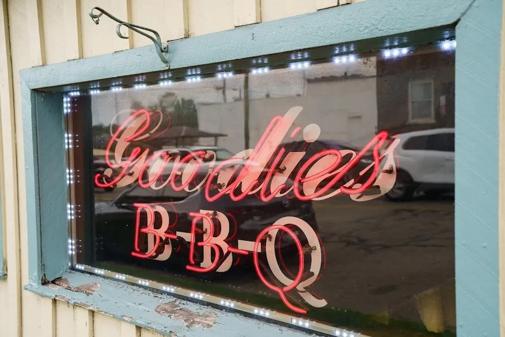 Close-up of a restaurant window with a red neon 'Goodies B-B-Q' sign.