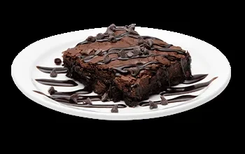 Fudgy chocolate brownie with sauce and chips on white plate, dark background.