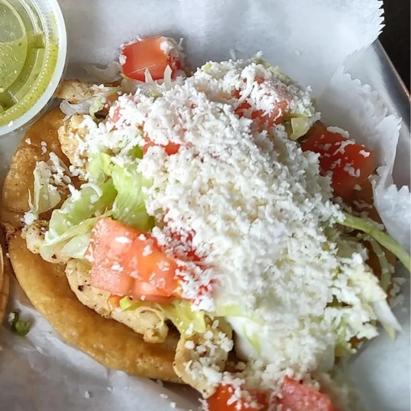 Deep-fried gordita with chicken, lettuce, tomato, cheese, and green sauce.