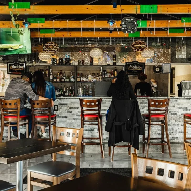 Well-lit casual bar with stacked stone, Modelo sign, and hanging lights.