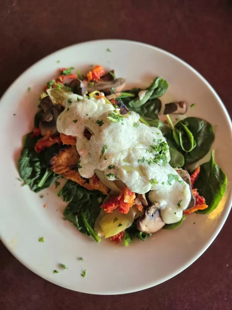 Overhead: Spinach, mushrooms, red peppers, protein, and creamy herb sauce.