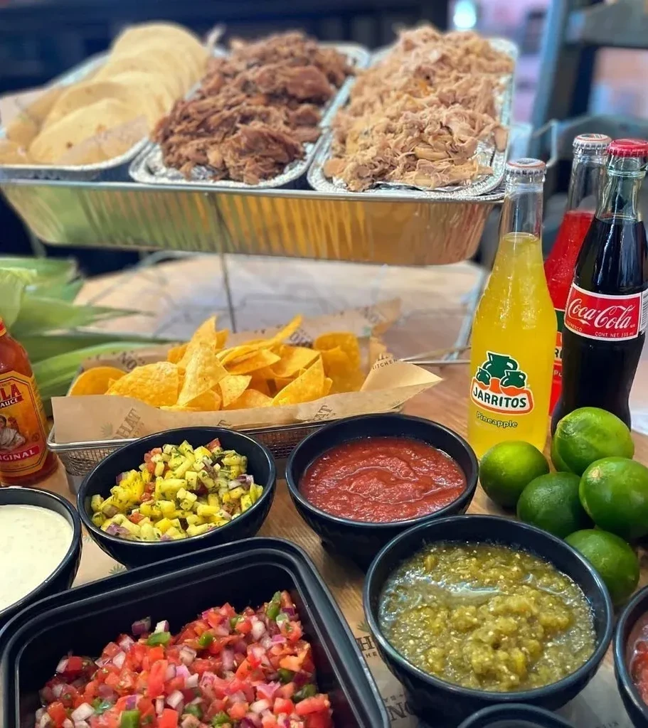 Abundant Mexican taco bar with meats, tortillas, salsas, chips, and drinks.