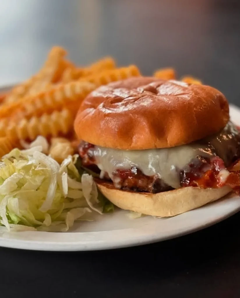 Gourmet hamburger with melted cheese, bacon, waffle fries, and lettuce.