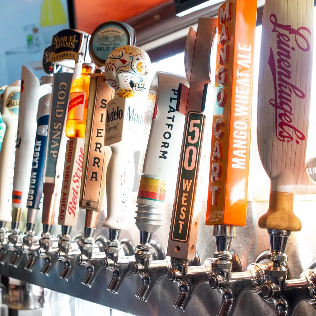 Close-up of multiple branded beer taps, one shaped like a colorful skull.