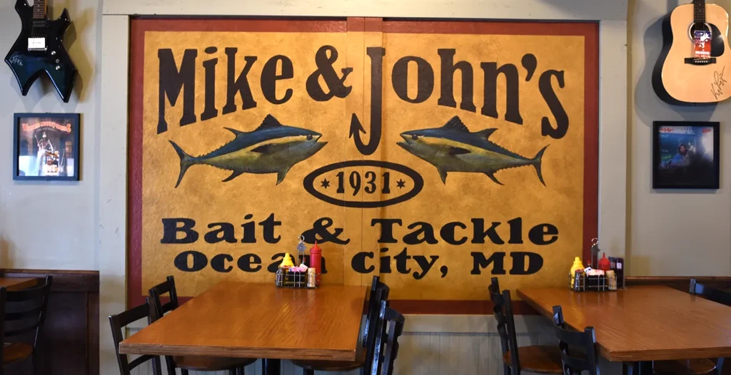Restaurant with 'Mike & John's Bait & Tackle' sign, guitars, and dining tables.