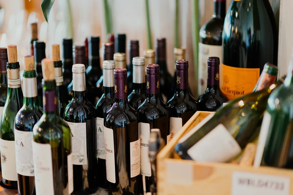 Densely packed red and white wine bottles, Veuve Clicquot in background.