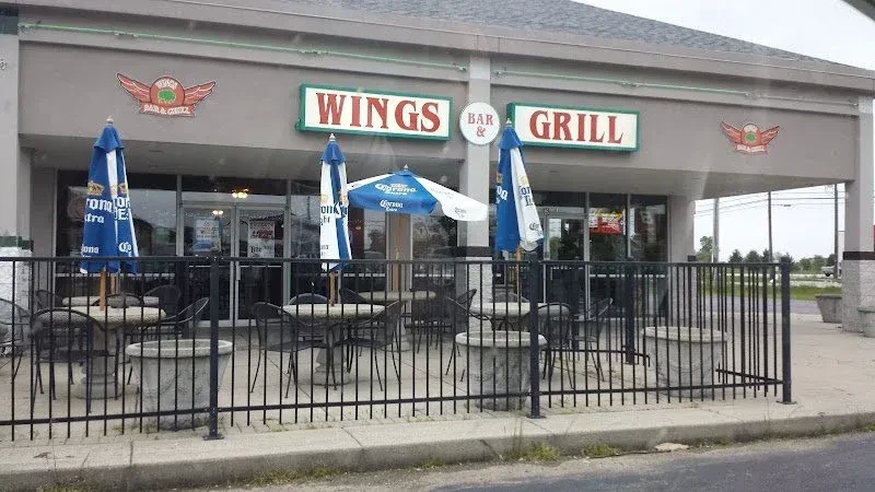 Wings Bar & Grill exterior patio with tables and Corona umbrellas.