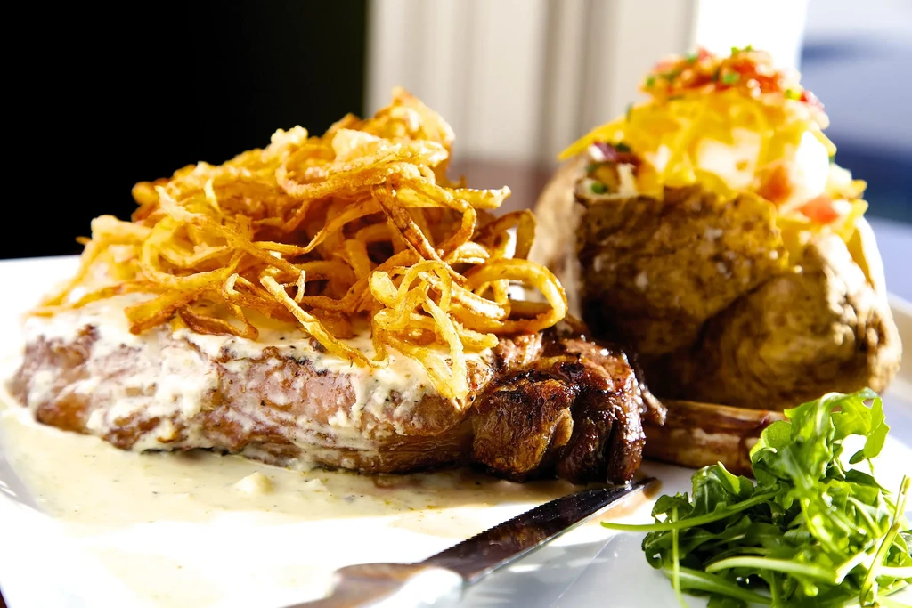 Thick steak, creamy sauce, fried onions, loaded baked potato, and arugula.