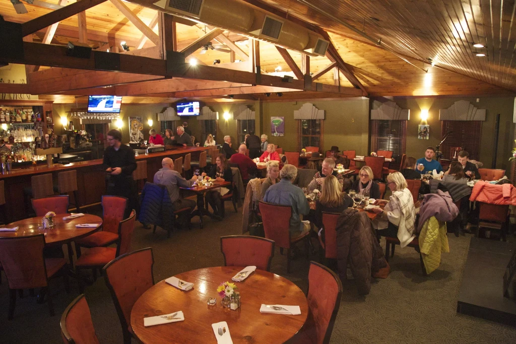 Warm, bustling restaurant interior with dining tables, bar, and rustic decor.