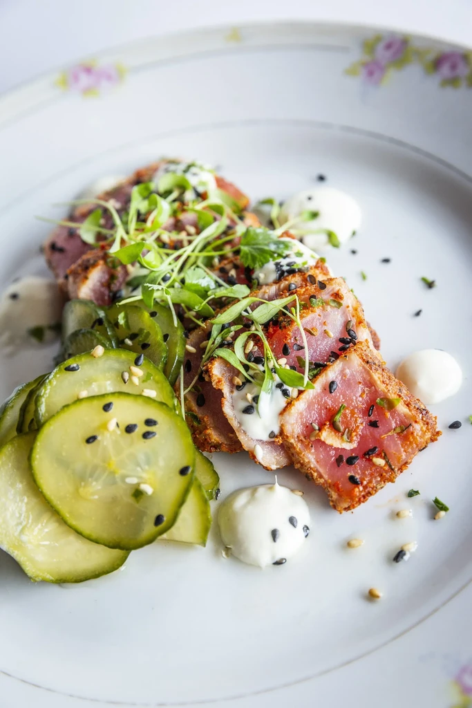 Plated seared tuna, microgreens, pickled vegetables, and creamy white sauce.