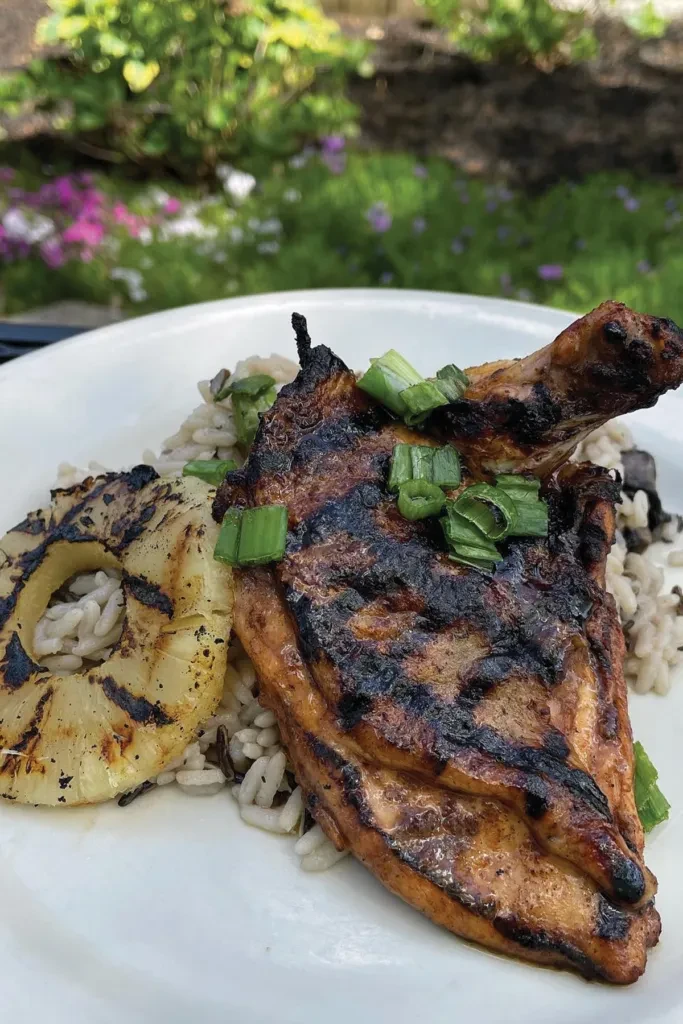 Charred grilled chicken, pineapple, rice, and green onions outdoors.