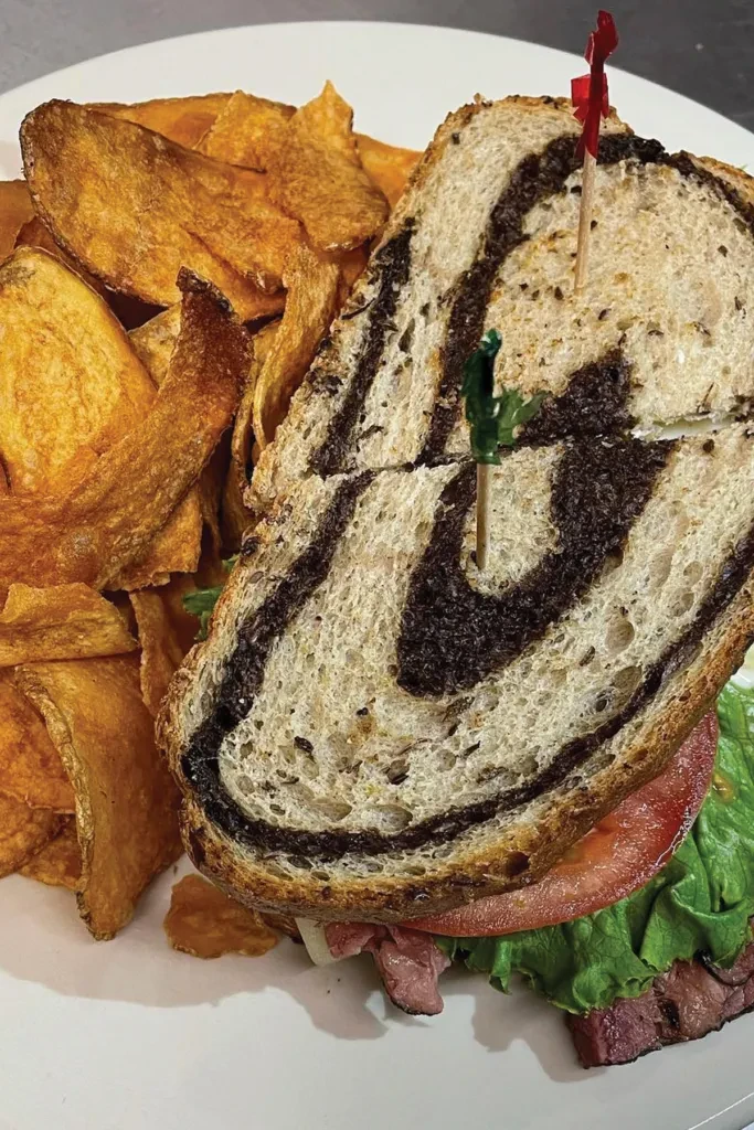 Close-up of a marbled deli sandwich and crispy potato chips.