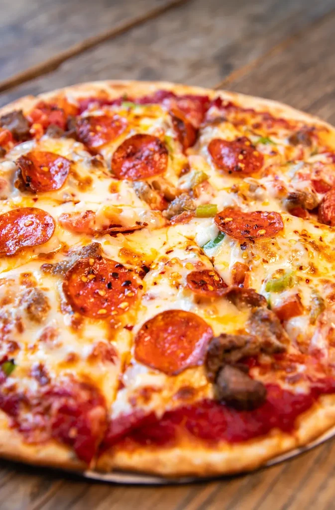 Close-up overhead supreme pizza with pepperoni, sausage, and green peppers.