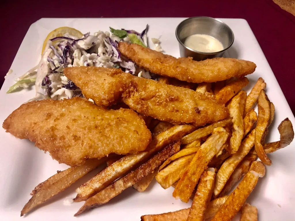 Golden battered fish and chips, coleslaw, lemon, and dipping sauce.