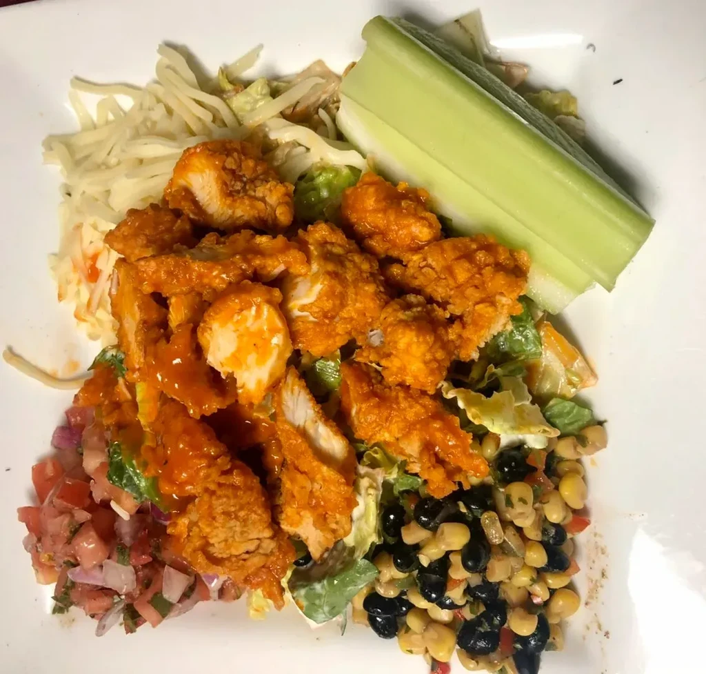Buffalo chicken on lettuce with celery, cheese, salsa, corn and beans.