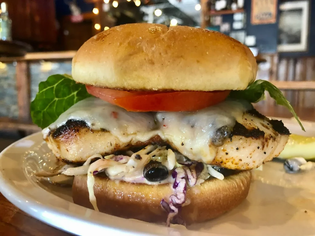 Grilled chicken or fish sandwich with cheese, tomato, lettuce, and pickle.