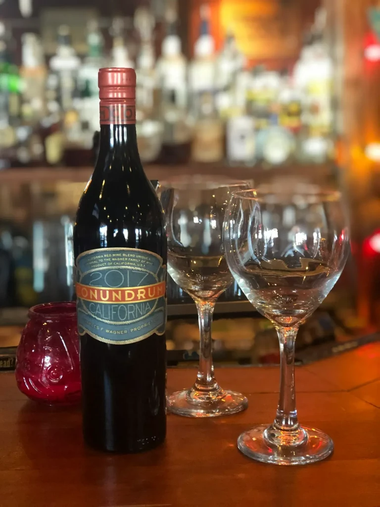 Conundrum California wine bottle, two glasses, on a lit bar.