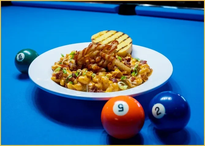 Macaroni and cheese with grilled bread on a pool table.