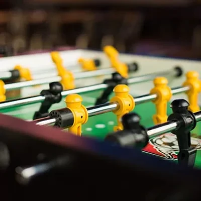 Foosball table close-up with yellow and black players on green field.