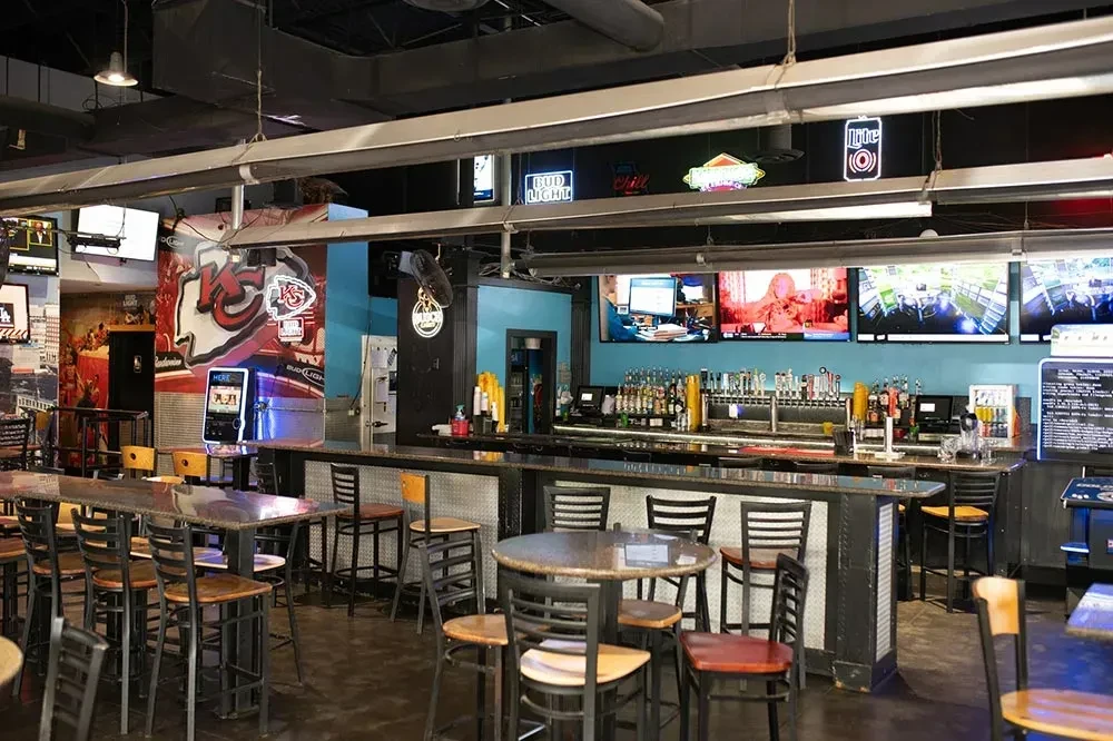 Inside a sports bar with beer taps, TVs, and Kansas City Chiefs mural.