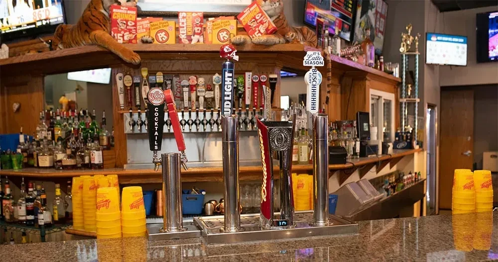 Sports bar interior with beer taps, liquor, TVs, and a stuffed tiger.