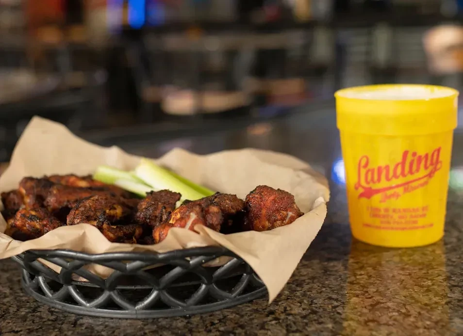 Chicken wings, celery, and a yellow cup reading "Landing Dirty Martini."