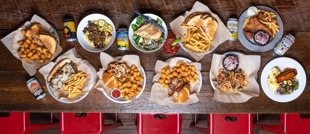 Overhead shot: rustic table with many comfort food plates and drinks.