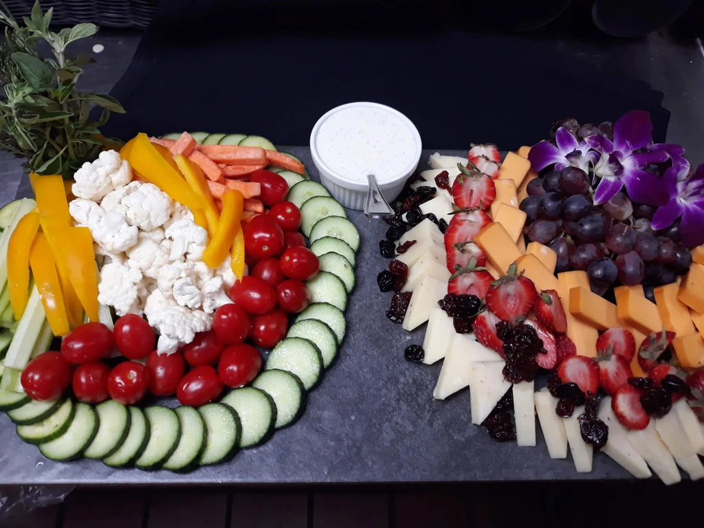 Two platters: fresh vegetables with dip, and fruits with cheeses.