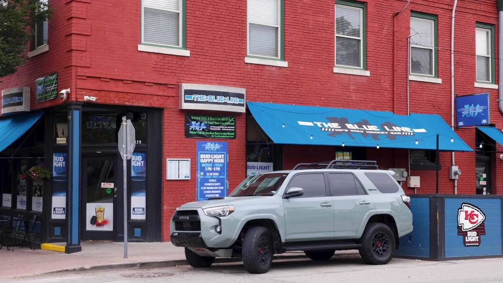 Exterior of The Blue Line, a red brick hockey bar with blue awnings.