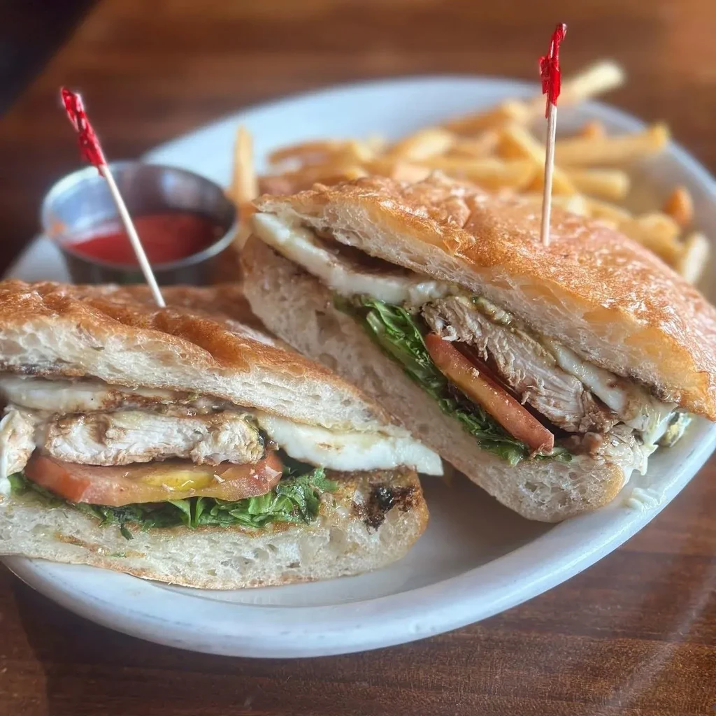Grilled chicken and cheese sandwich, cut in half, with french fries.