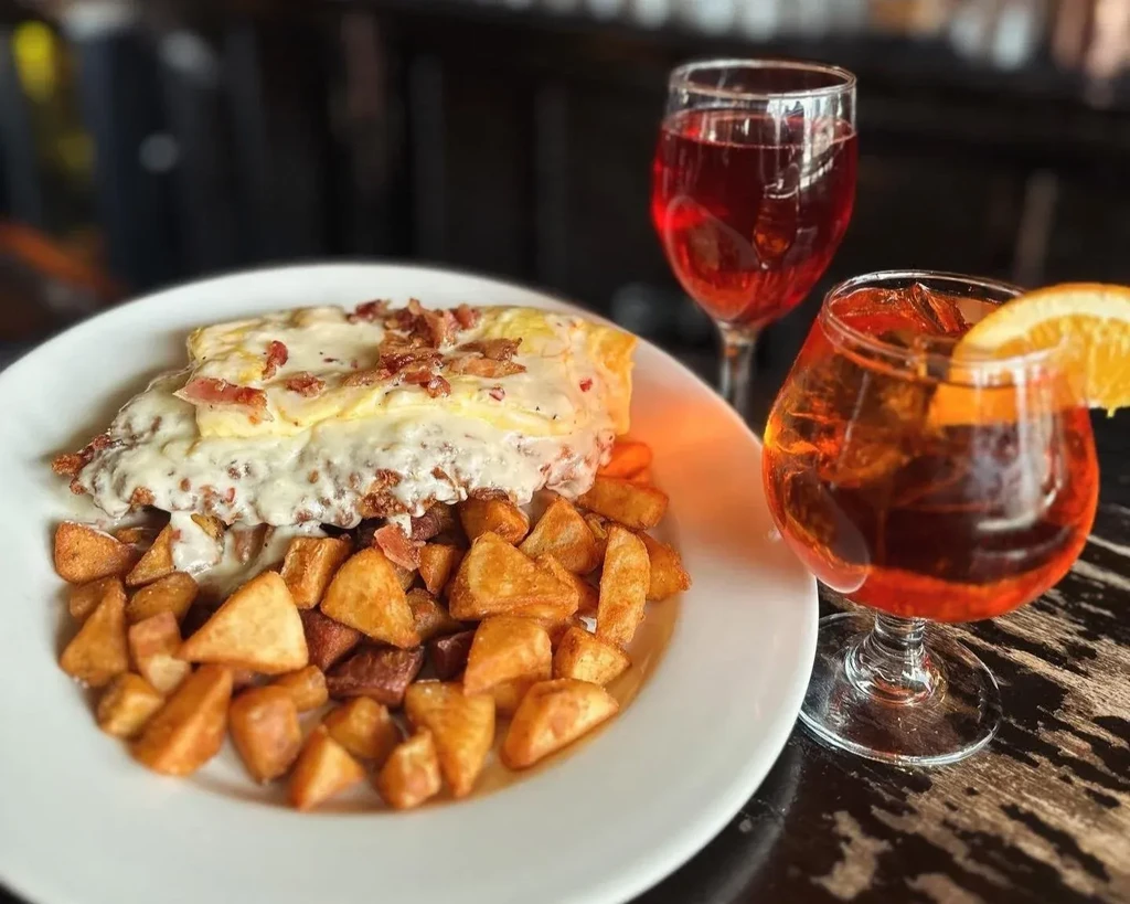 Close-up of gravy-covered meal with fries, red and orange drinks.