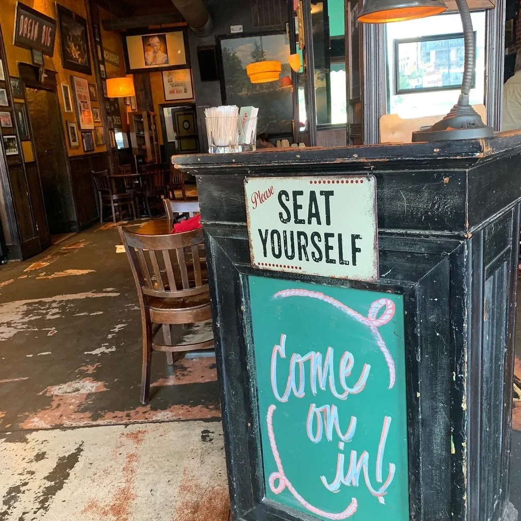 Rustic restaurant interior with a "Please SEAT YOURSELF" sign.